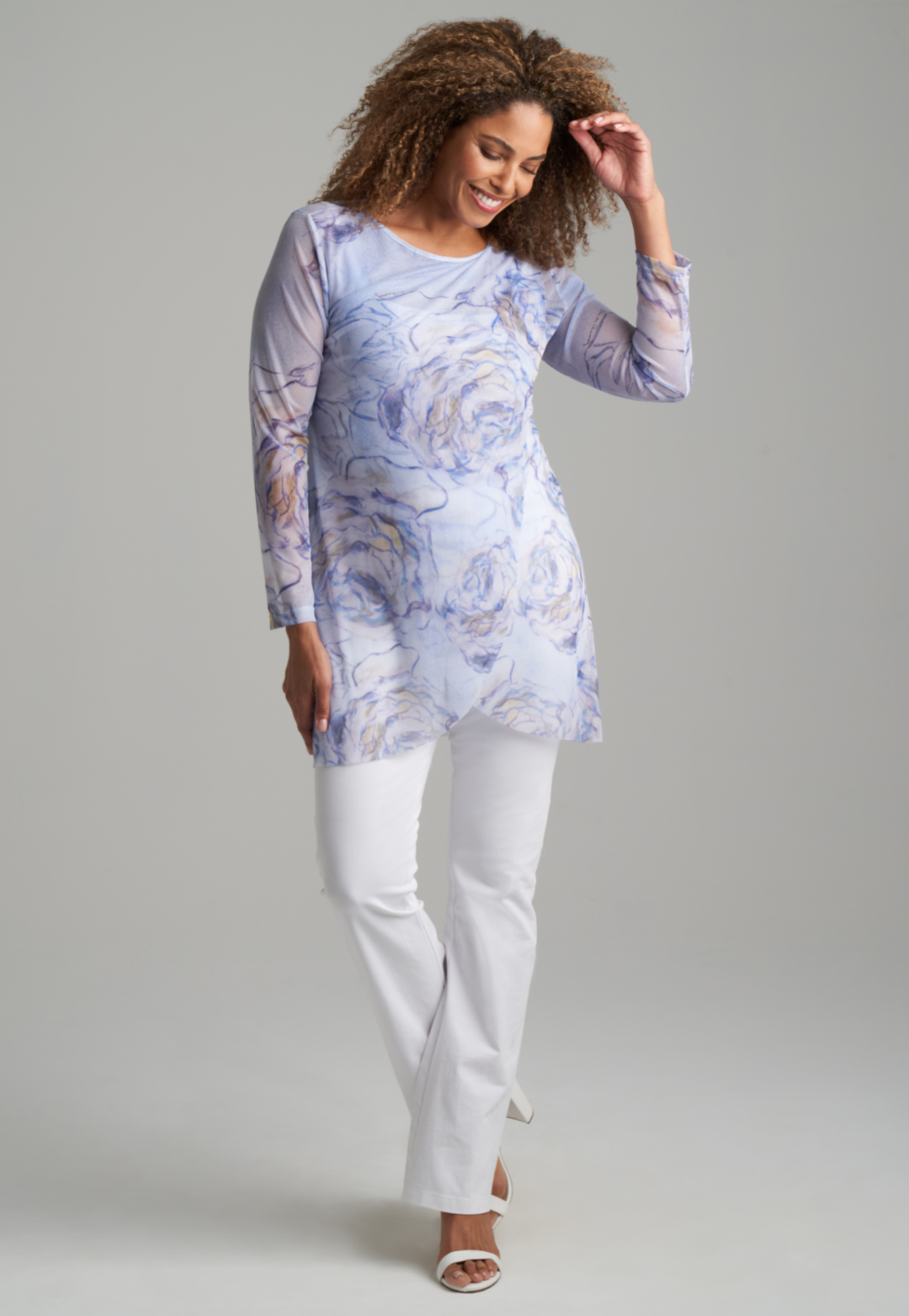 Woman wearing blue rose printed mesh tunic over white stretch knit tank top and pants by Ala von Auersperg for spring summer 2022