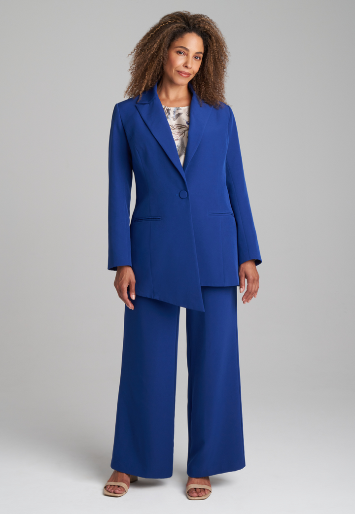 Woman wearing blue silk lined blazer over silk feather printed shell tank top and blue stretch knit pants suite by Ala von Auersperg for fall 2022