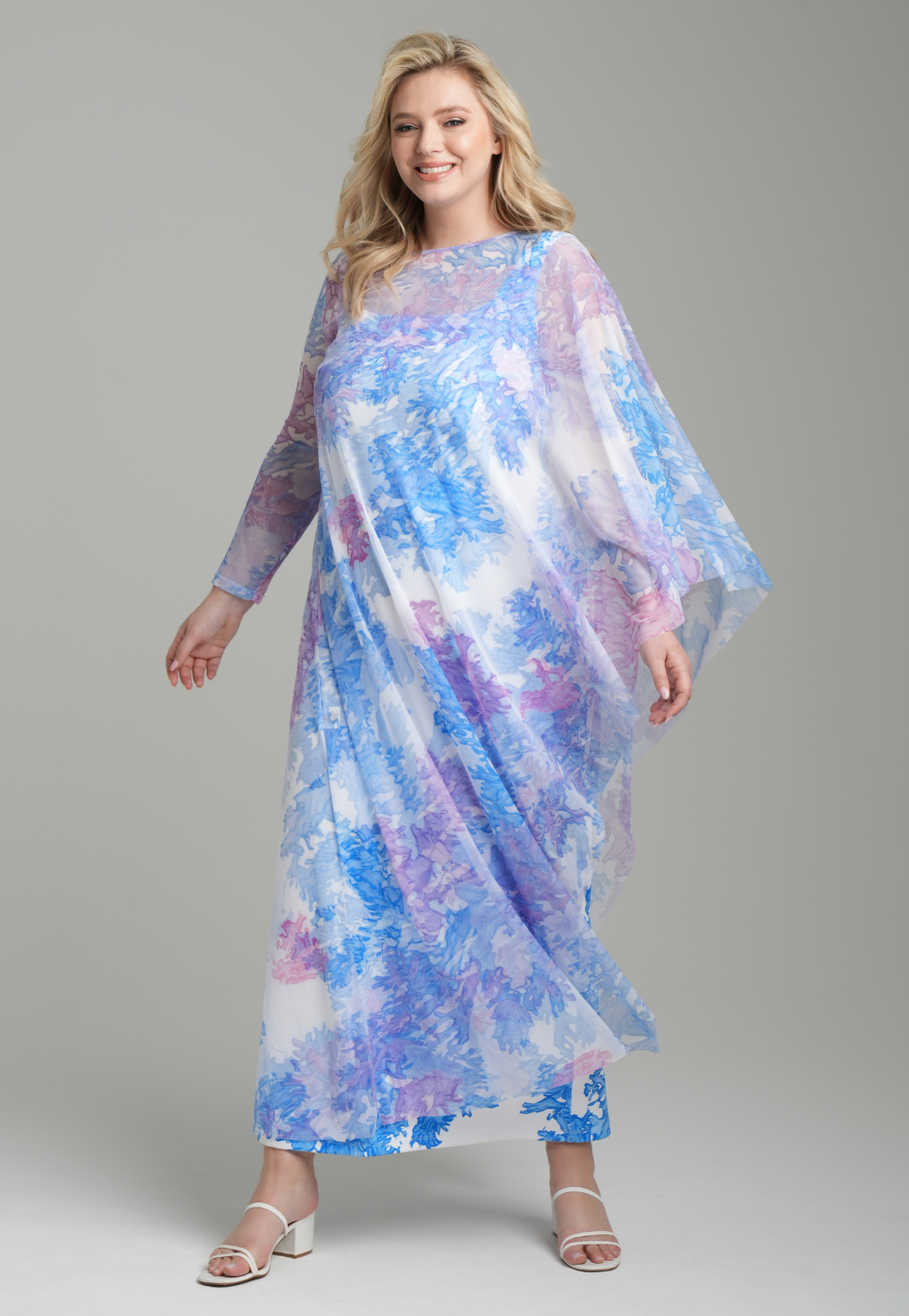 Woman wearing rainbow coral printed one armed mesh kaftan poncho over blue coral printed stretch knit long tank dress by Ala von Auersperg for resort 2023