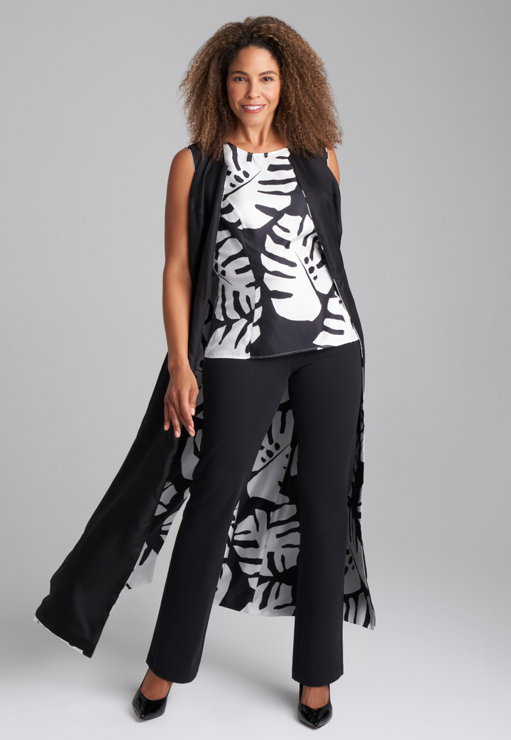 Woman wearing black and white palm leaf printed silk shell tank top with italian stretch cotton black pants  and reversible silk palm leaf black and white printed long vest by Ala von Auersperg for holiday 2022