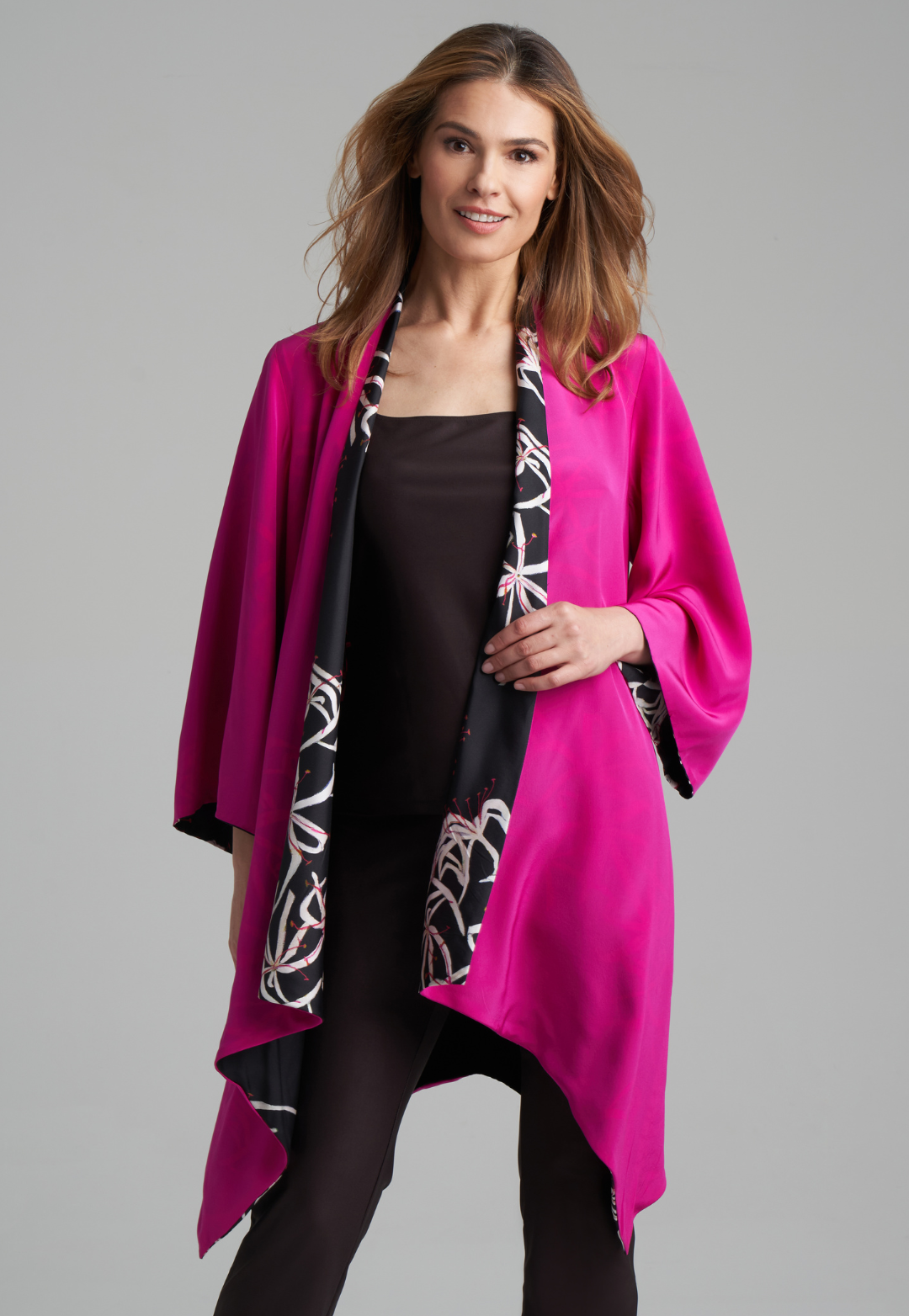 Woman wearing silk black spider lily printed reversible pink robe jacket over black stretch knit tank top and pant by Ala von Auersperg