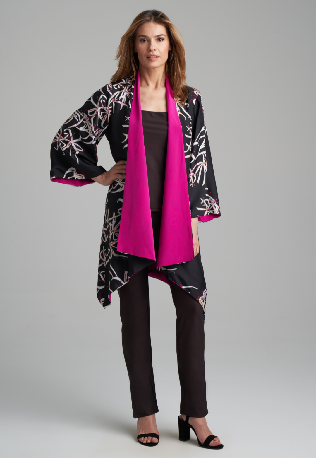 Woman wearing silk black spider lily printed reversible pink robe jacket over black stretch knit tank top and pant by Ala von Auersperg