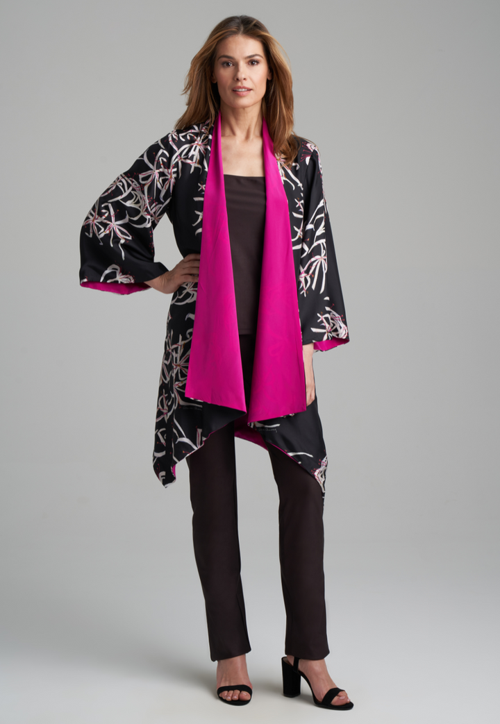 Woman wearing silk black spider lily printed reversible pink robe jacket over black stretch knit tank top and pant by Ala von Auersperg