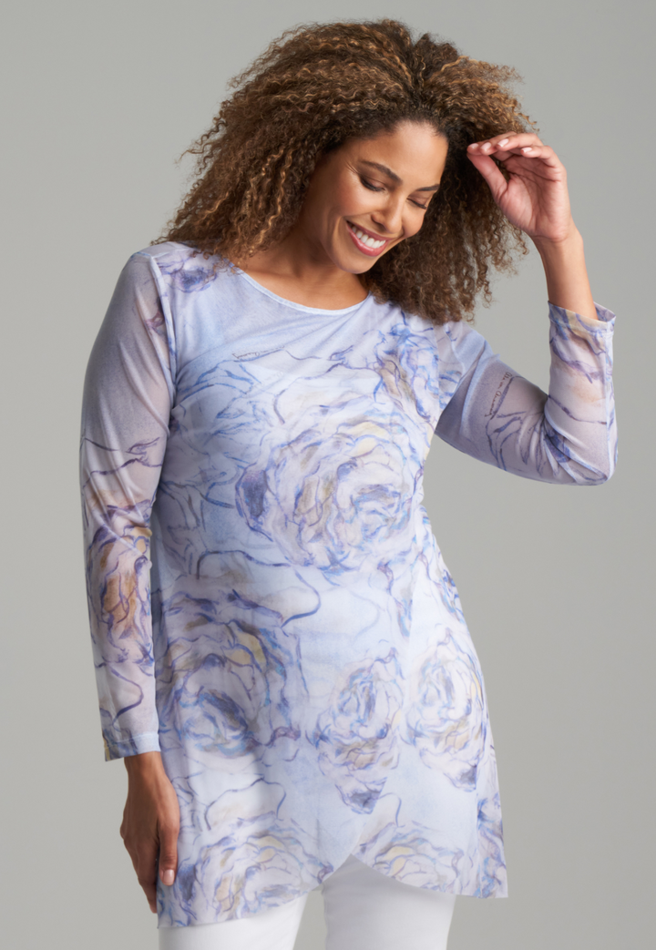 Woman wearing blue rose printed mesh tunic over white stretch knit tank top and pants by Ala von Auersperg for spring summer 2022