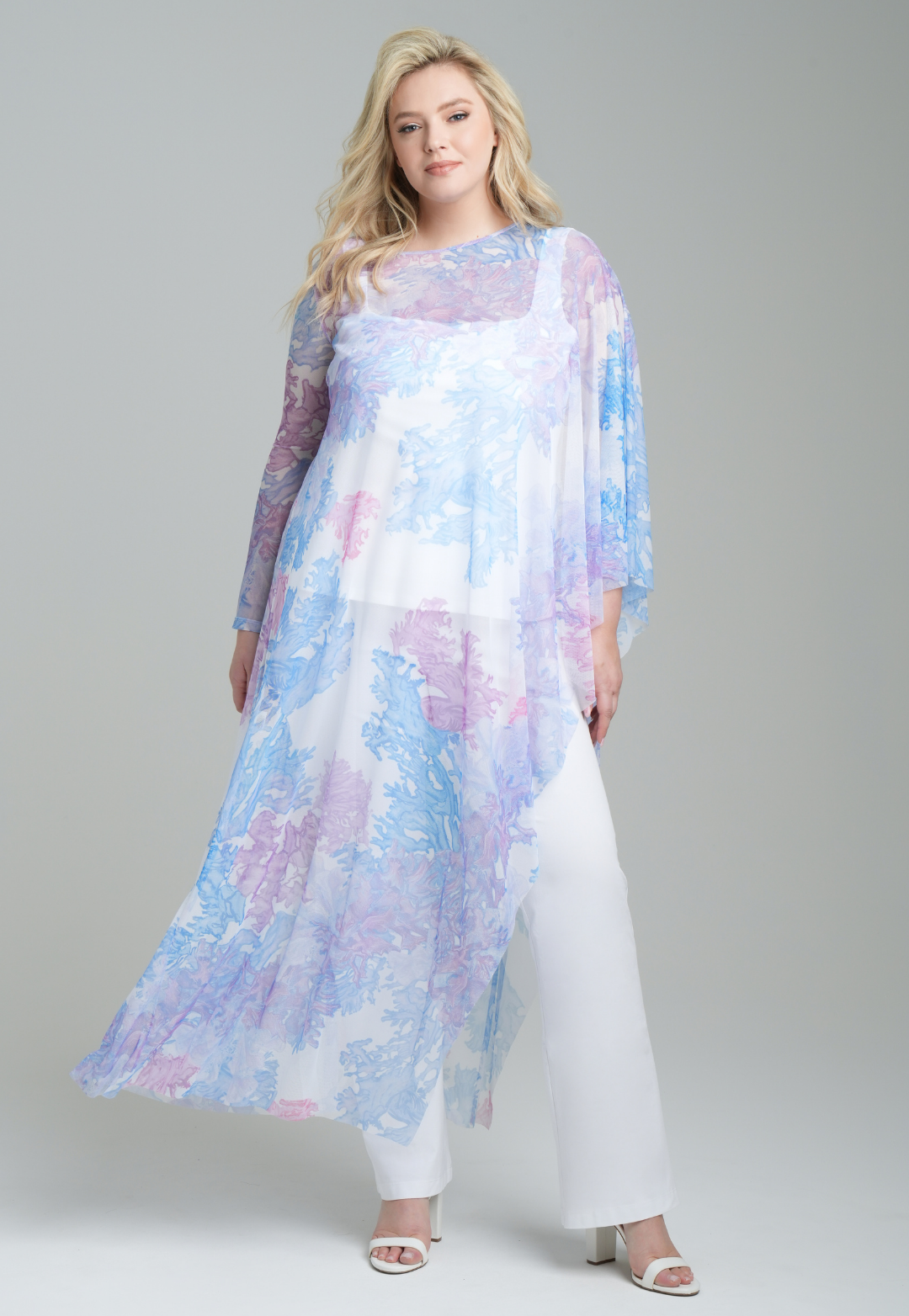 Woman wearing rainbow coral printed mesh one armed kaftan poncho over italian stretch cotton white tank top and pants by Ala von Auersperg for resort 2023