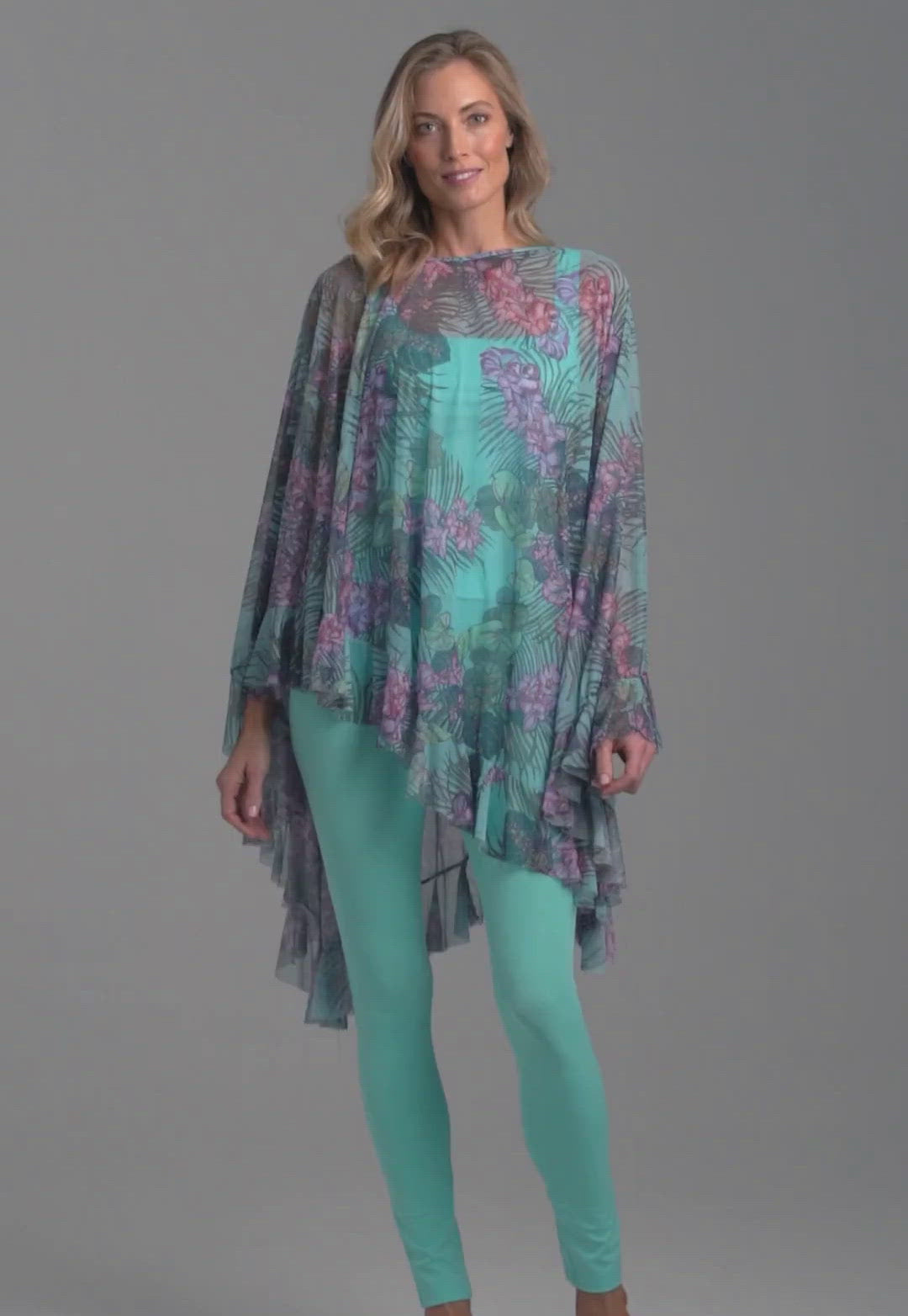Woman wearing mesh printed orchid and palm poncho over stretch knit tank top and stretch knit pant printed in orchid and palm
