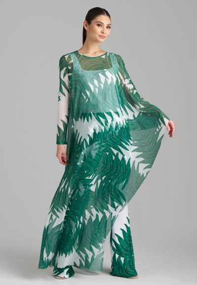 Woman wearing on armed mesh green palm leaf printed kaftan poncho over italian stretch cotton white tank top and green palm leaf printed stretch knit pants by Ala von Auersperg