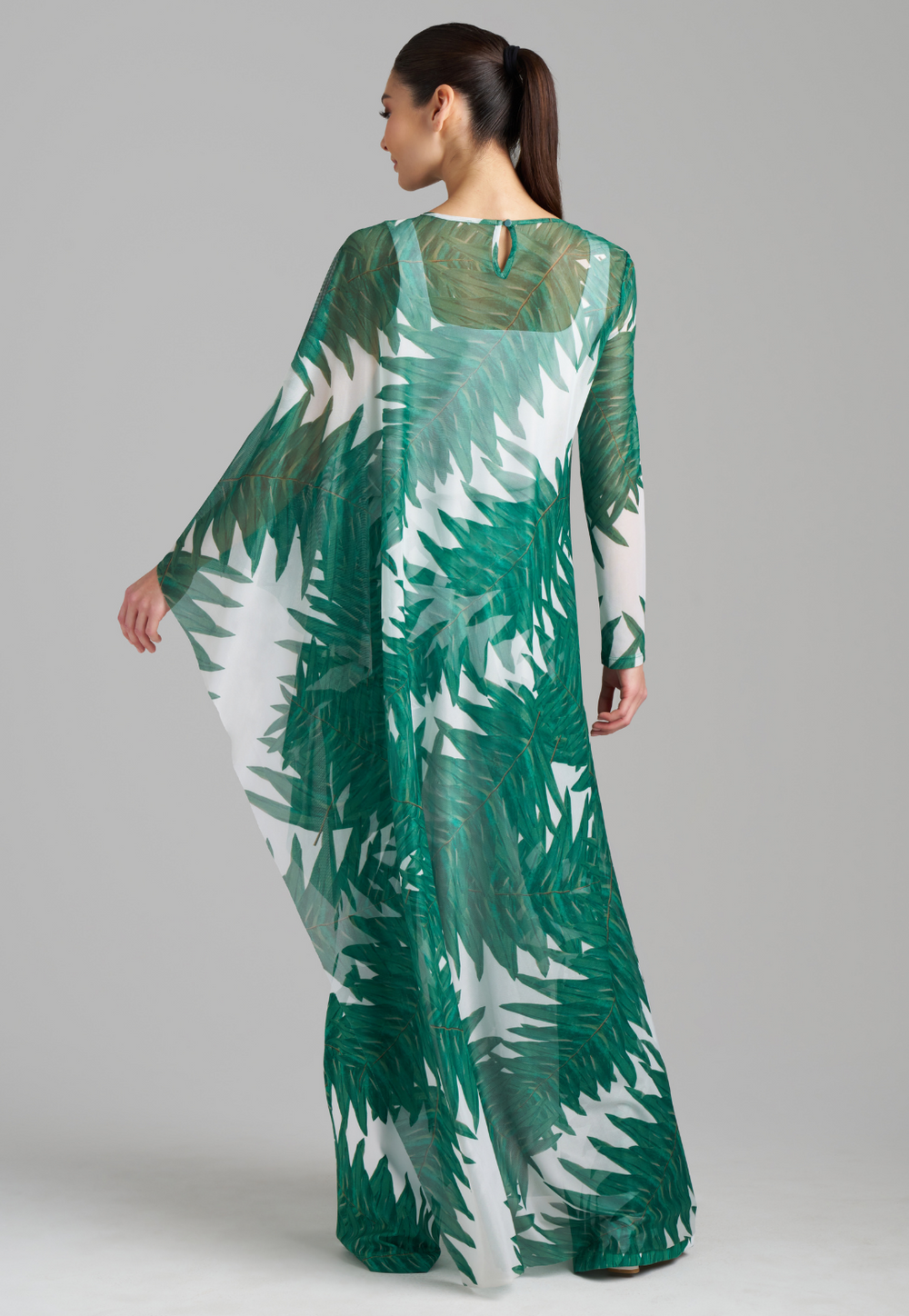 Woman wearing on armed mesh green palm leaf printed kaftan poncho over italian stretch cotton white tank top and green palm leaf printed stretch knit pants by Ala von Auersperg