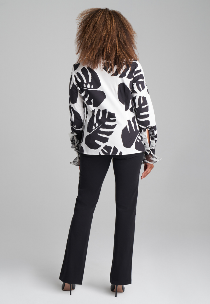 Woman wearing cotton turtleneck black and white palm leaf printed blouse with ruffle sleeve and collar details with italian stretch cotton pant in black by Ala von Auersperg for holiday 2022