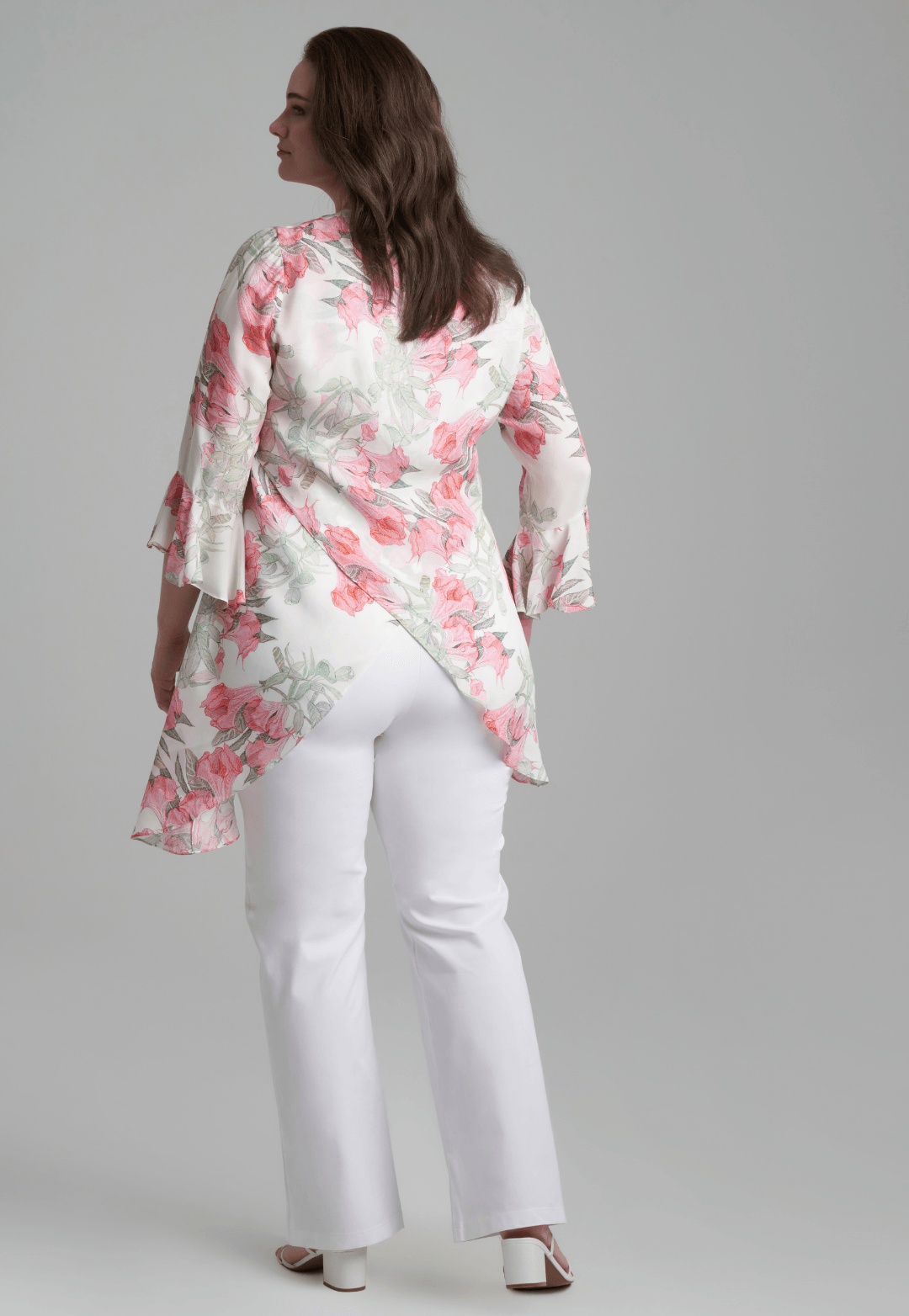 Woman wearing silk asymmetrical flower printed blouse with stretch knit white pants by Ala von Auersperg for spring summer 2022