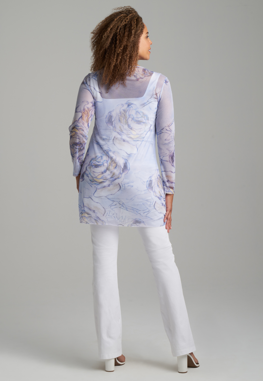 Woman wearing blue rose printed mesh tunic over white stretch knit tank top and pants by Ala von Auersperg for spring summer 2022