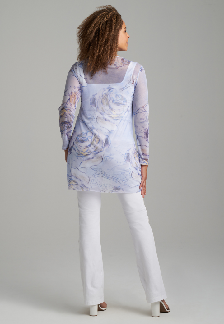 Woman wearing blue rose printed mesh tunic over white stretch knit tank top and pants by Ala von Auersperg for spring summer 2022