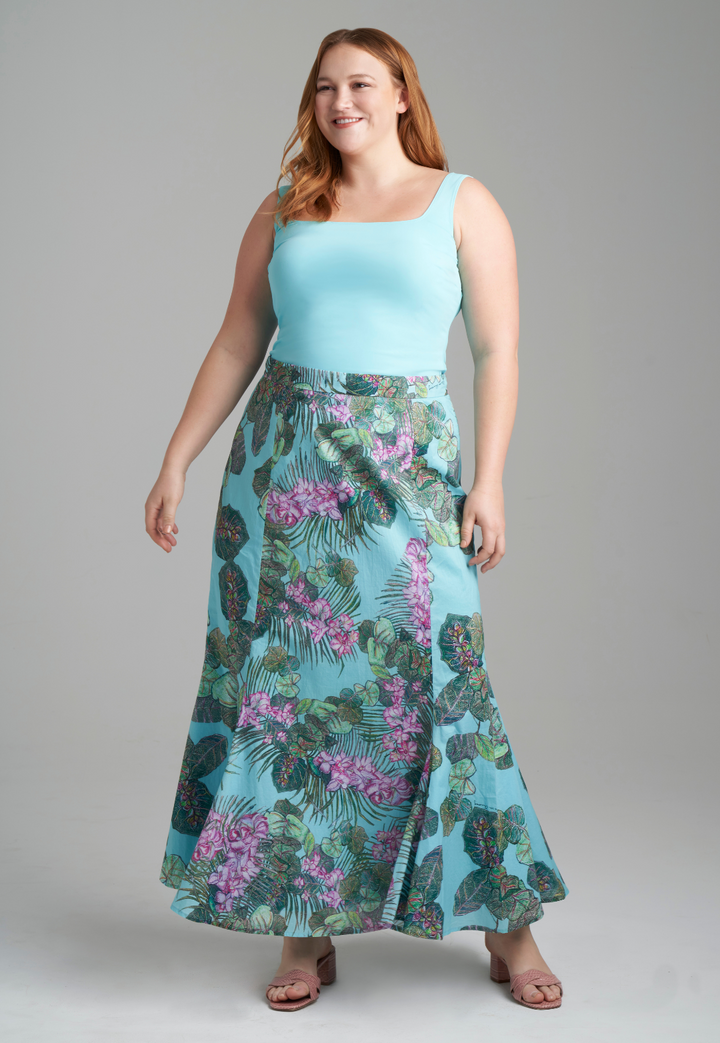 Woman wearing blue stretch knit square neck tank top with cotton grape leaf and orchid printed green cotton peasant skirt by Ala von Auersperg for resort 2022