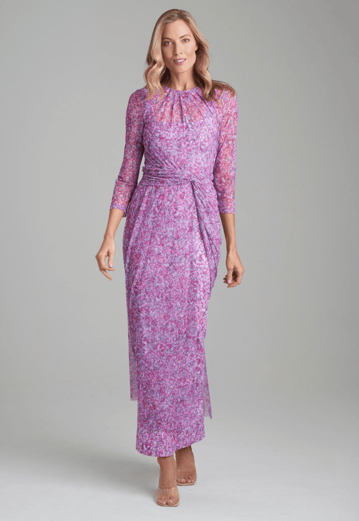 Woman wearing Mesh asymmetrical topper in printed pink orchid flowers over long printed orchid flower stretch knit dress by Ala von Auersperg for resort 2022