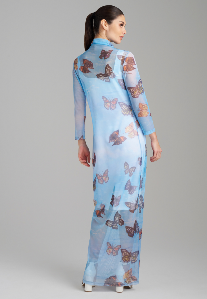 Woman wearing long mesh t shirt dress with turtleneck color in blue butterfly print over a short white stretch knit dress by Ala von Auersperg for spring 2023