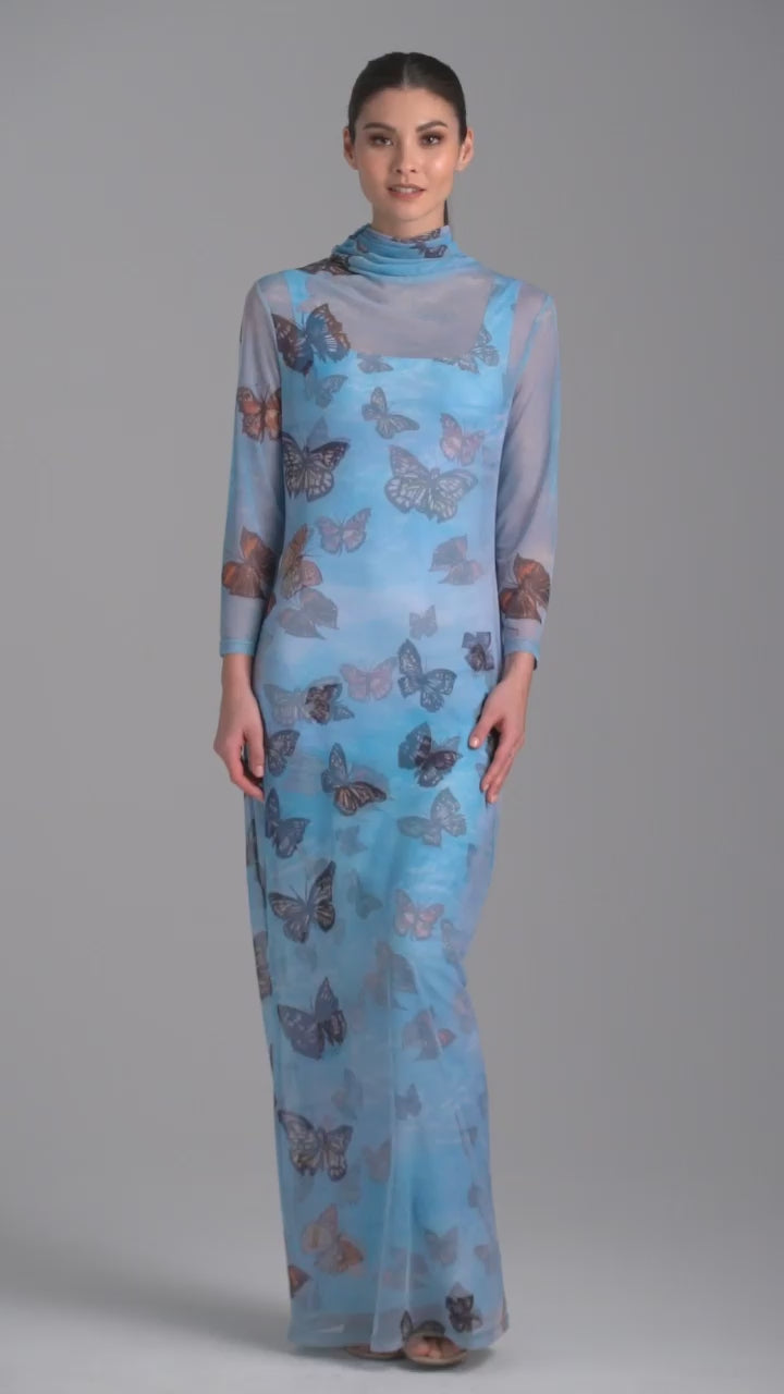 Woman wearing long mesh t shirt dress with turtleneck in blue butterfly printed over long stretch knit blue butterfly print dress by Ala von Auersperg for spring 2023
