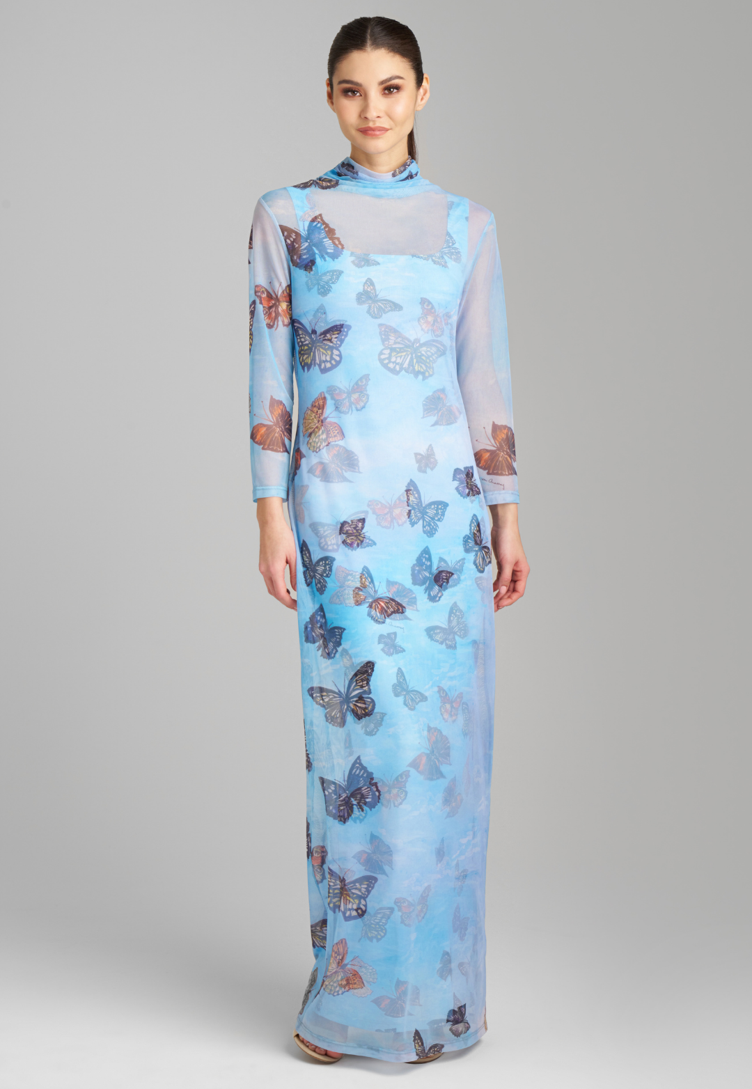 Woman wearing long mesh t shirt dress with turtleneck in blue butterfly printed over long stretch knit blue butterfly print dress by Ala von Auersperg for spring 2023