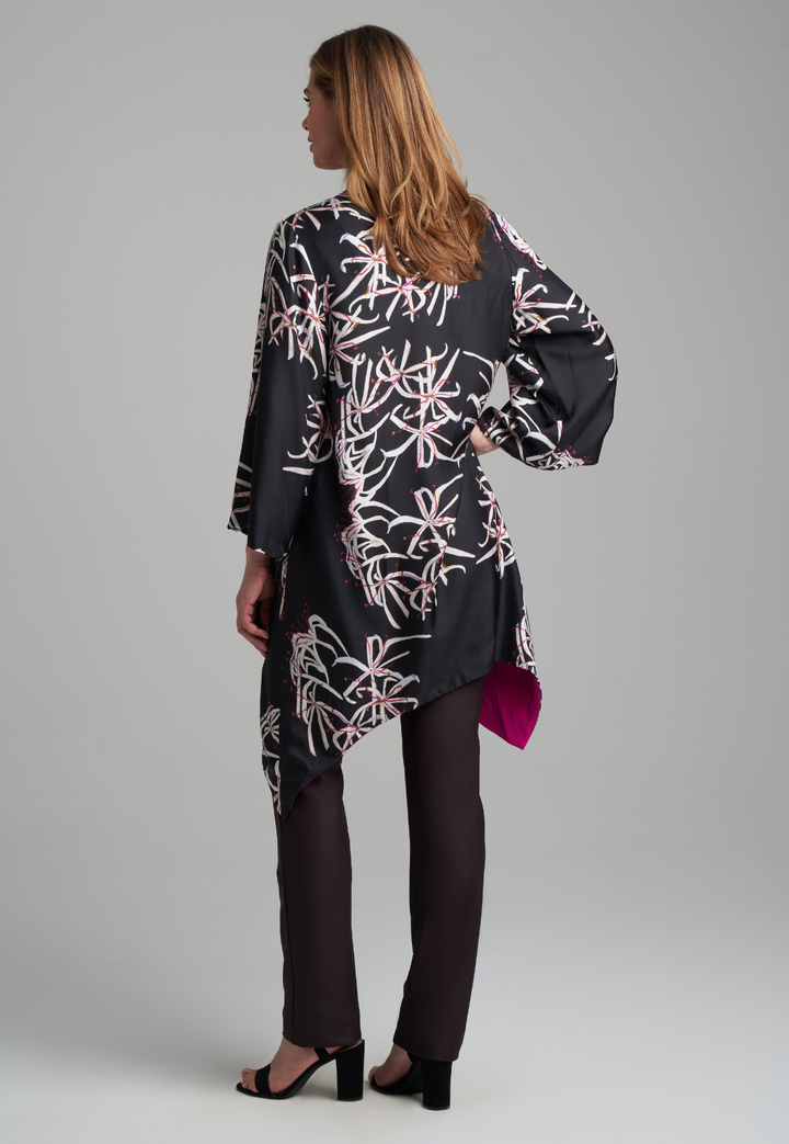 Woman wearing silk black spider lily printed reversible pink robe jacket over black stretch knit tank top and pant by Ala von Auersperg