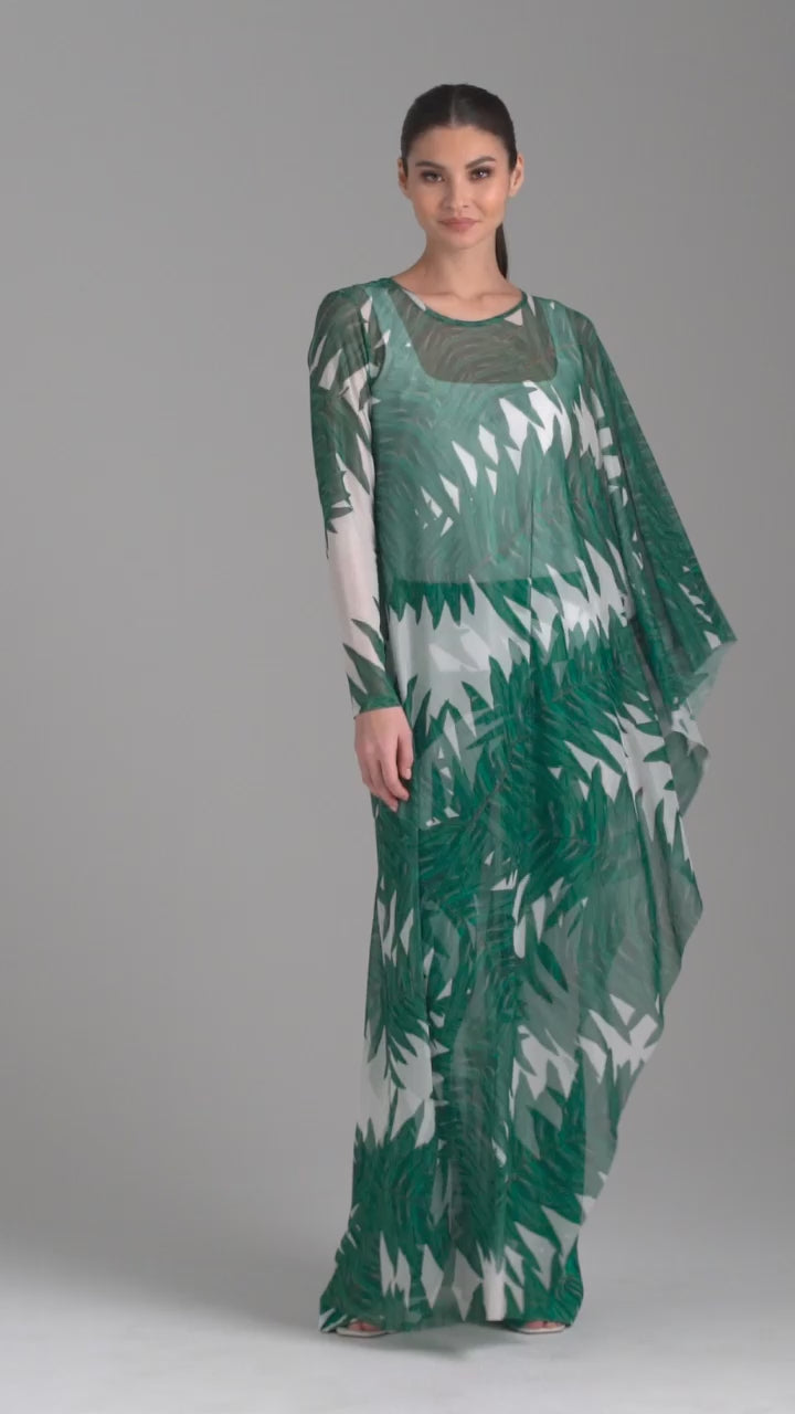 Woman wearing on armed mesh green palm leaf printed kaftan poncho over italian stretch cotton white tank top and green palm leaf printed stretch knit pants by Ala von Auersperg