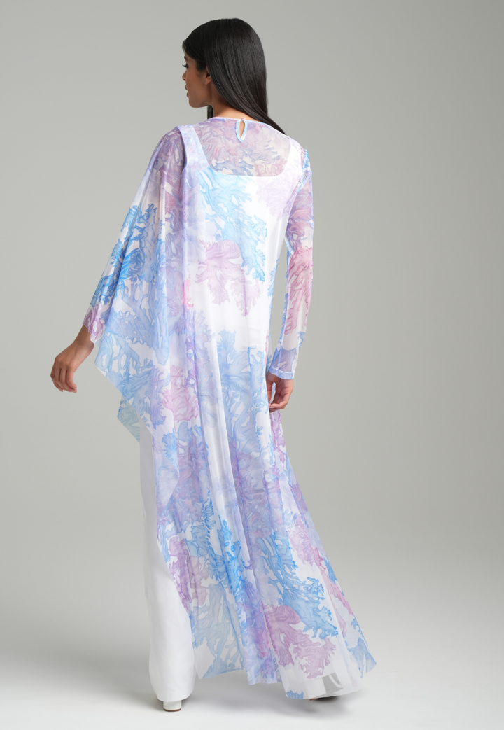 Woman wearing rainbow coral printed mesh one armed kaftan poncho over italian stretch cotton white tank top and pants by Ala von Auersperg for resort 2023