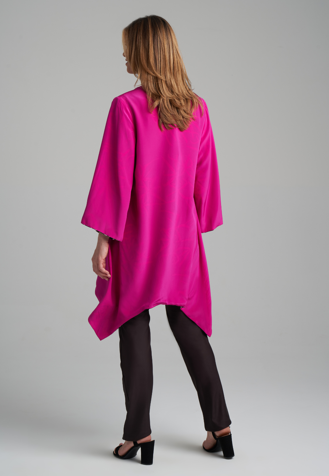 Woman wearing silk black spider lily printed reversible pink robe jacket over black stretch knit tank top and pant by Ala von Auersperg