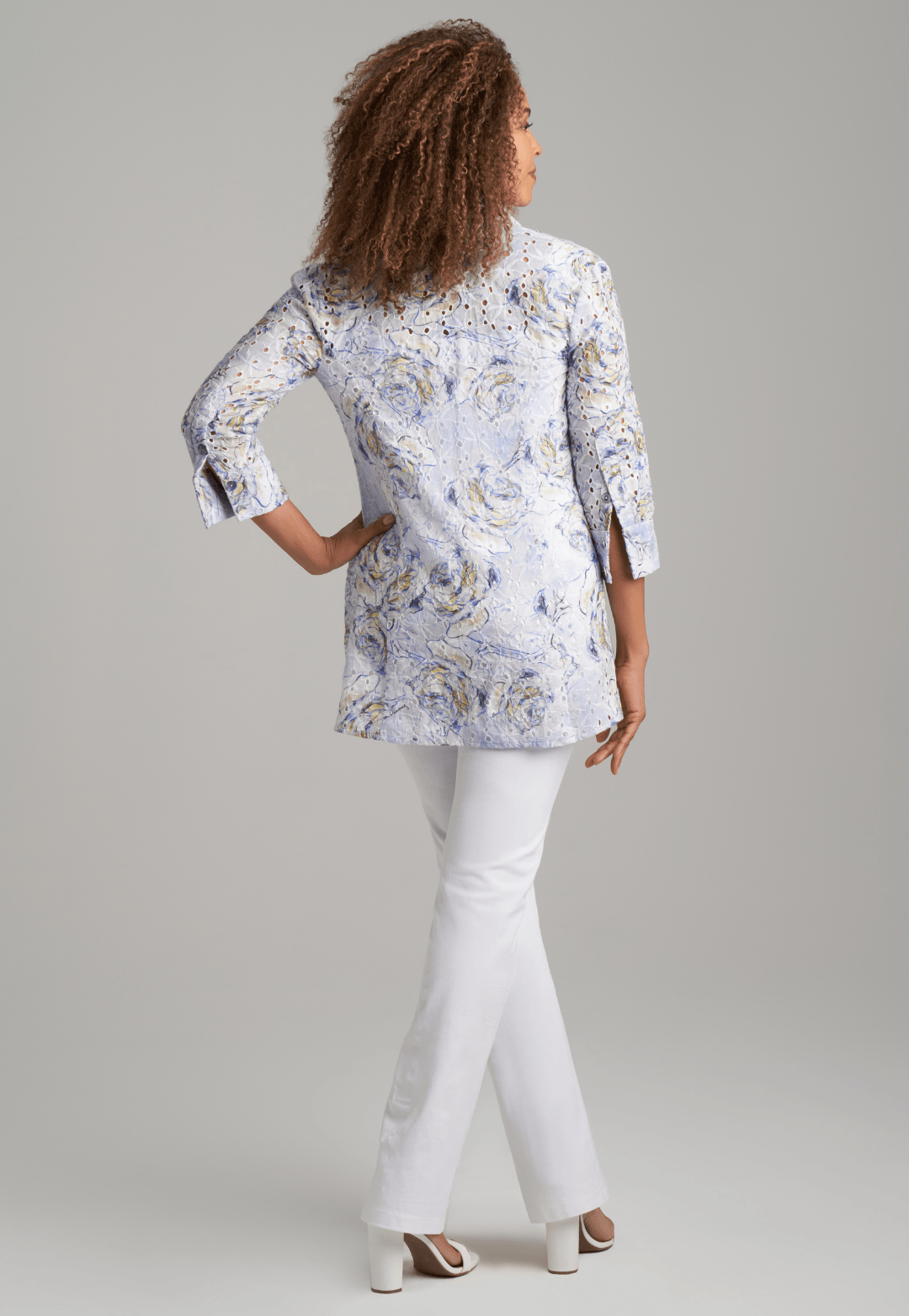 Woman wearing blue rose printed cotton eyelet safari shirt jacket with white stretch knit pants by Ala von Auersperg for spring summer 2022