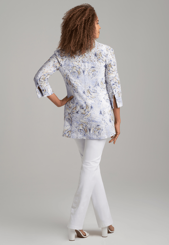 Woman wearing blue rose printed cotton eyelet safari shirt jacket with white stretch knit pants by Ala von Auersperg for spring summer 2022