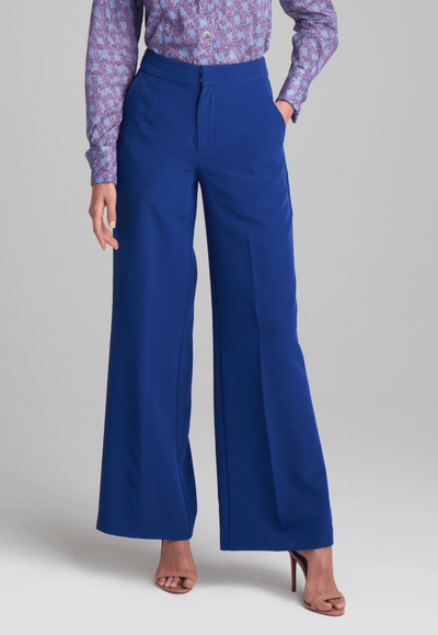 Woman wearing purple and blue bird printed cotton blouse and stretch knit blue pants by Ala von Auersperg for fall 2022 