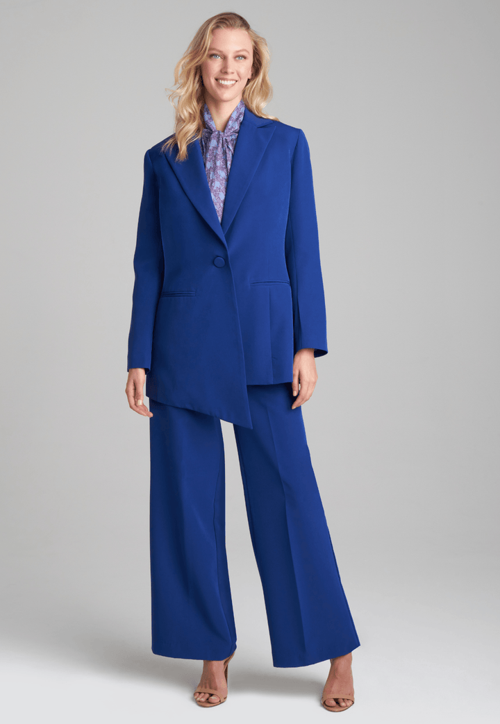 Woman wearing silk lined sapphire blazer with printed cotton bow tie blouse and stretch blue pants suite by Ala von Auersperg for fall 2022