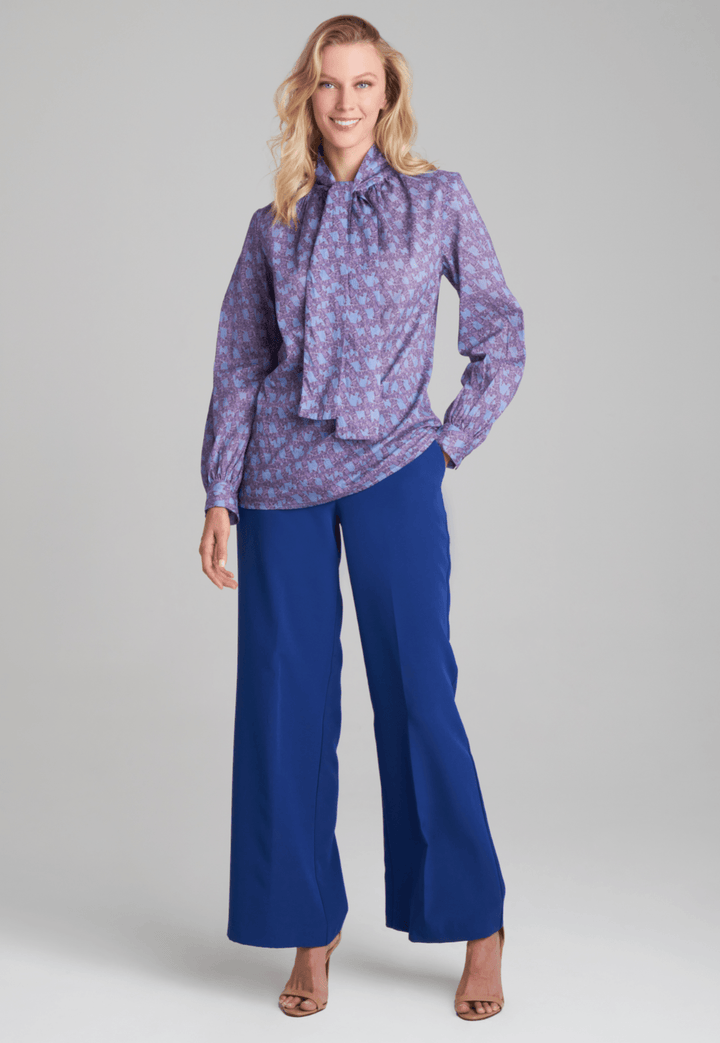 Woman wearing purple and blue bird printed cotton blouse and stretch knit blue pants by Ala von Auersperg for fall 2022 