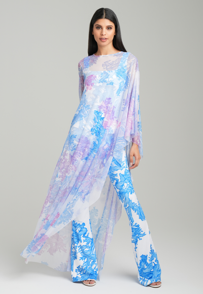 Woman wearing rainbow coral printed one armed mesh kaftan poncho over blue coral printed stretch knit tank top and pants by Ala von Auersperg for resort 2023