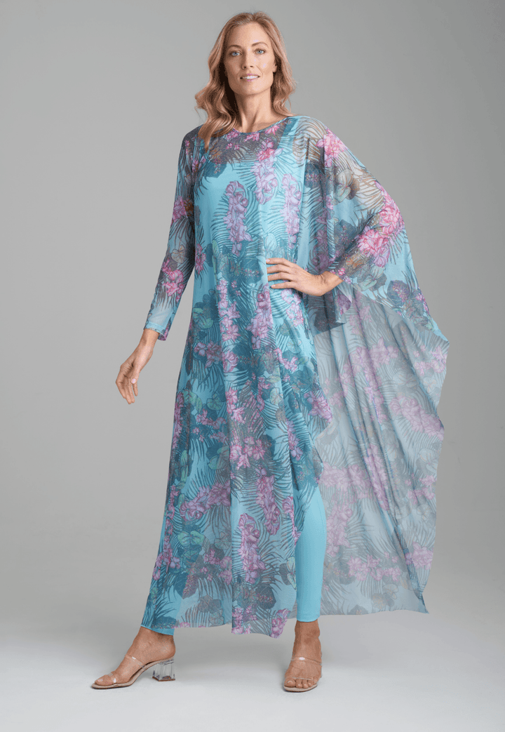 Woman wearing stretch knit solid blue green tank top with printed mesh orchid and palm one sleeve kaftan by Ala von Auersperg for resort 2022