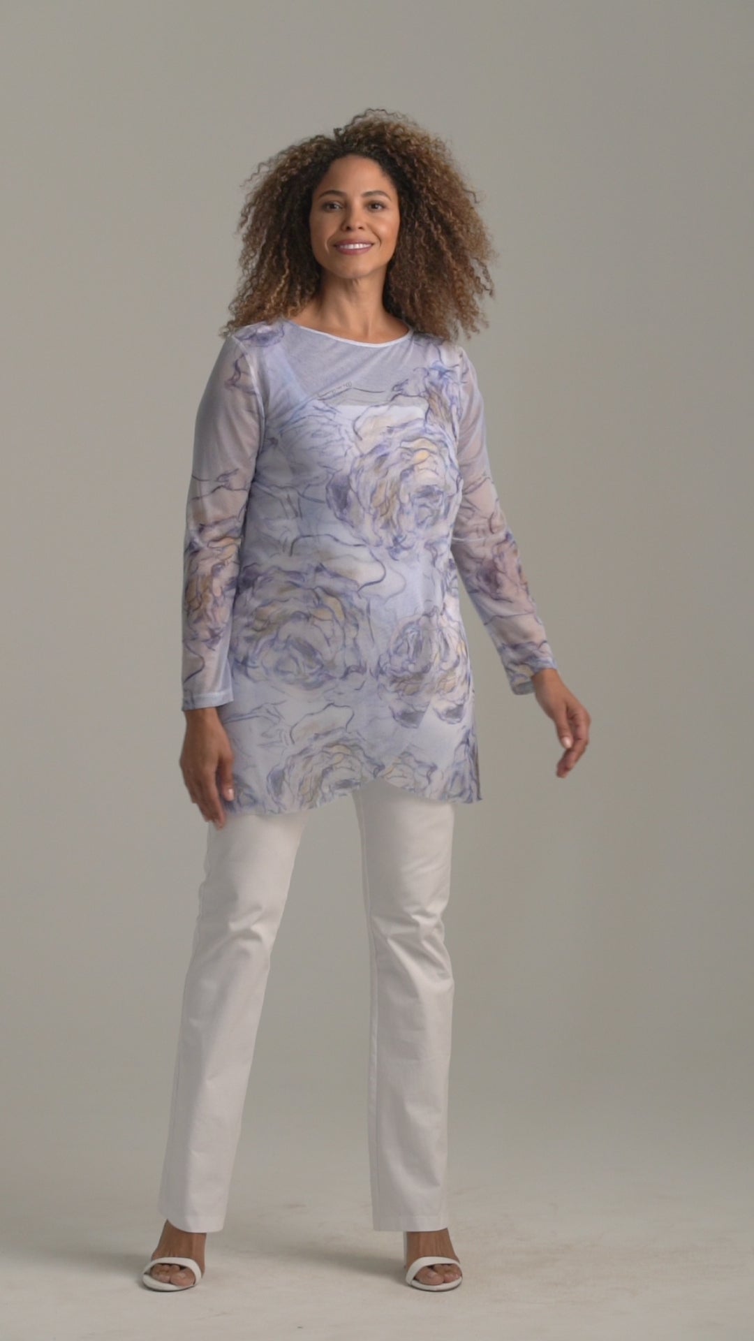 Woman wearing blue rose printed mesh tunic over white stretch knit tank top and pants by Ala von Auersperg for spring summer 2022