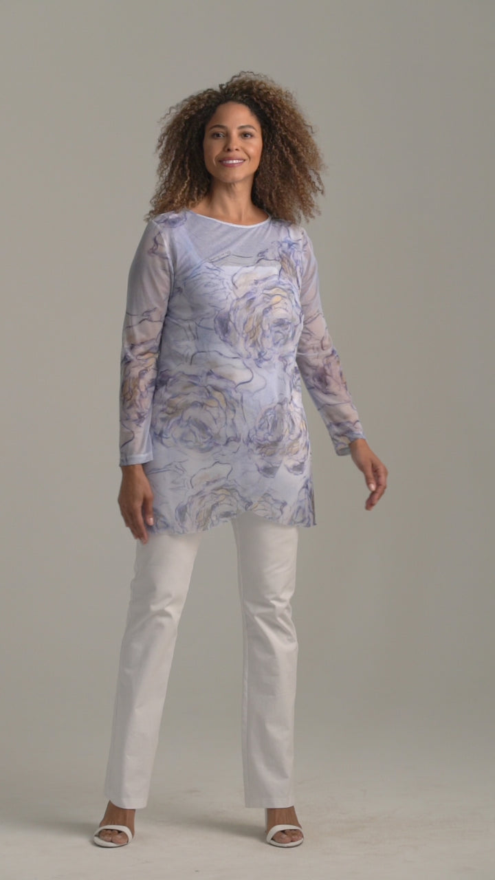 Woman wearing blue rose printed mesh tunic over white stretch knit tank top and pants by Ala von Auersperg for spring summer 2022
