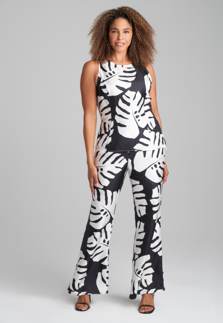 Woman wearing black and white palm leaf printed silk shell tank top and palm leaf black and white leaf printed silk wide leg pants by Ala von Auersperg for holiday 2022