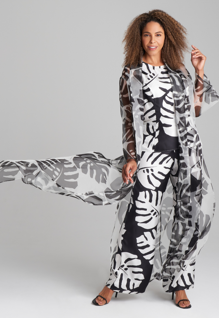 Woman wearing long silk palm leaf printed reversible long vest over silk palm leaf printed black and white shell tank top and wide leg silk pants by Ala von Auersperg for holiday 2022