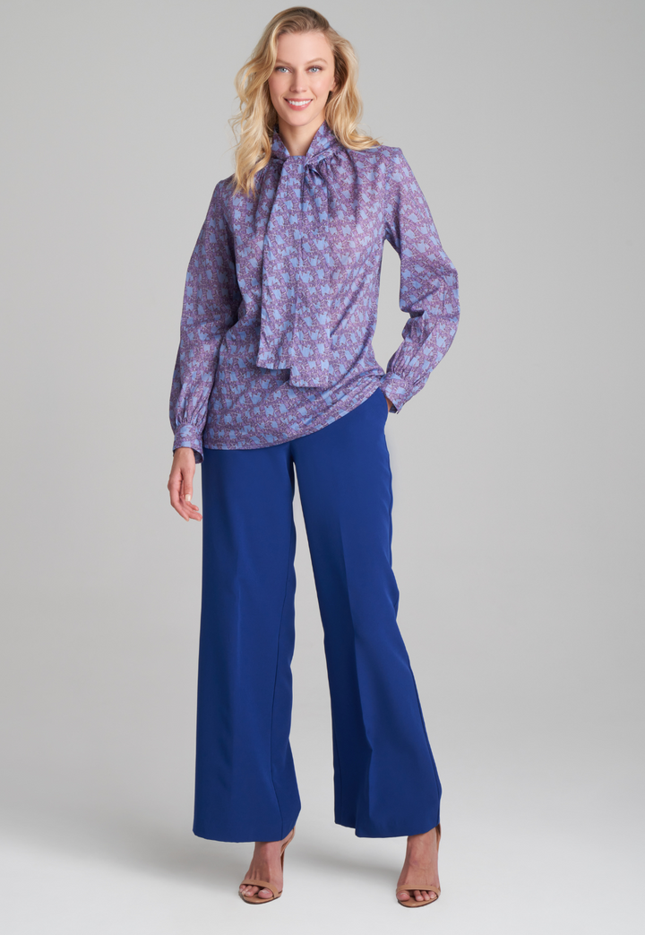 Woman wearing purple and blue bird printed cotton blouse and stretch knit blue pants by Ala von Auersperg for fall 2022