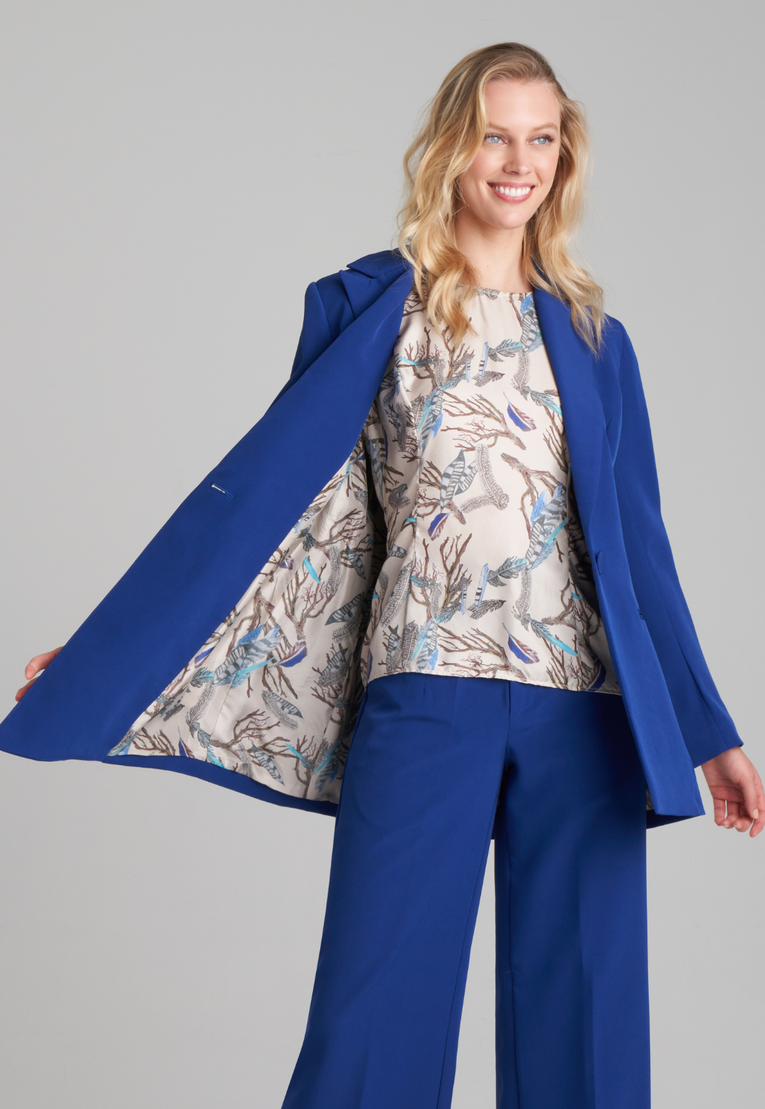 Woman wearing silk lined sapphire blazer with printed silk shell tank top and stretch blue pants suite by Ala von Auersperg for fall 2022