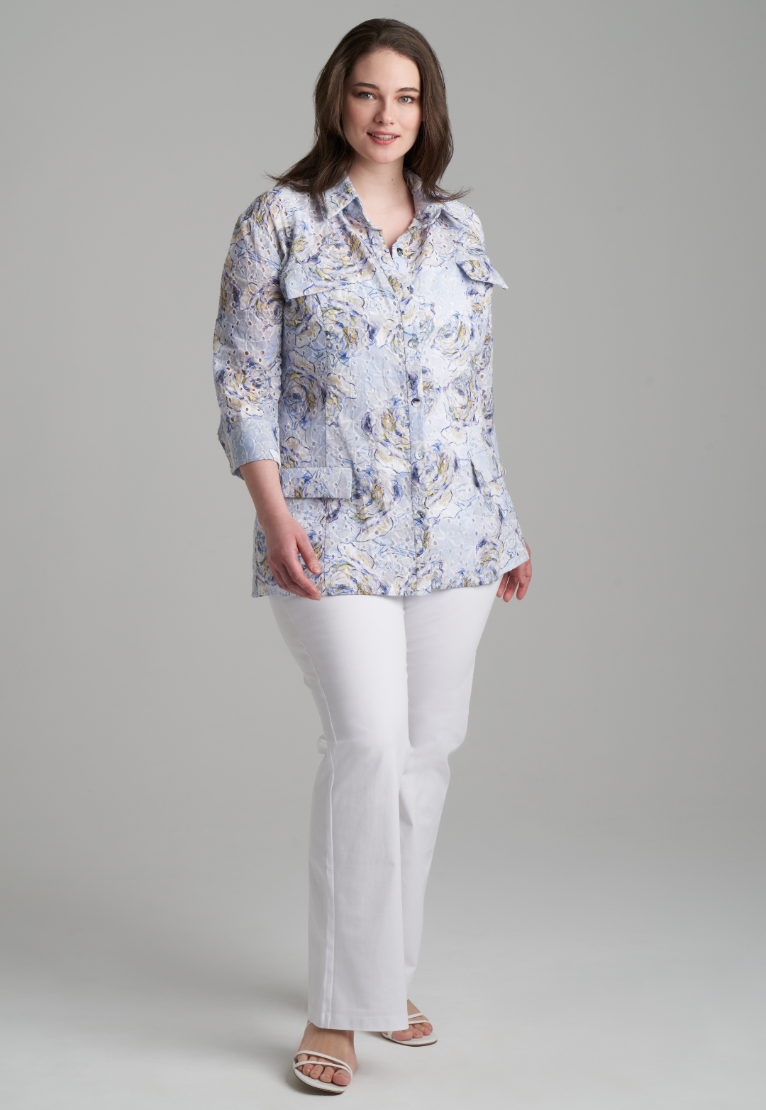 Woman wearing blue rose printed cotton eyelet safari shirt jacket with white stretch knit pants by Ala von Auersperg for spring summer 2022