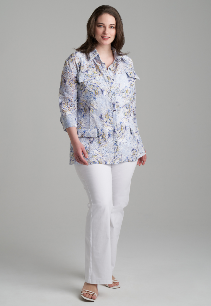 Woman wearing blue rose printed cotton eyelet safari shirt jacket with white stretch knit pants by Ala von Auersperg for spring summer 2022