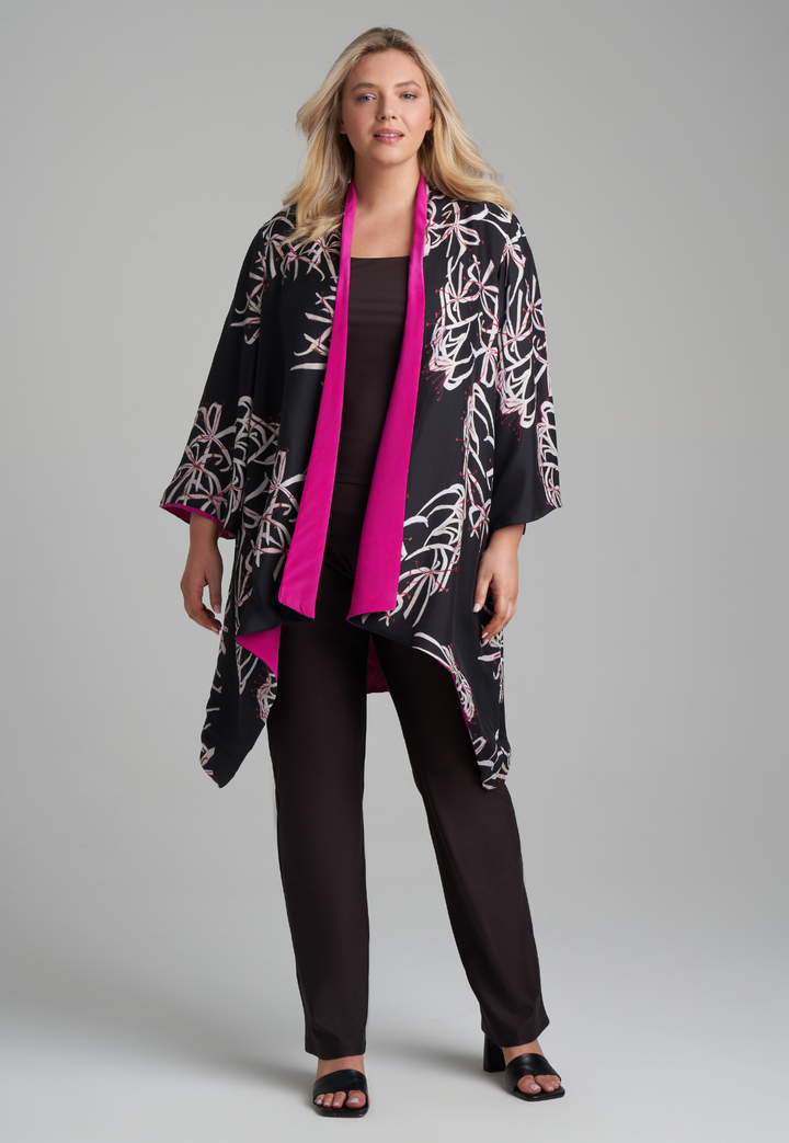 Woman wearing silk black spider lily printed reversible pink robe jacket over black stretch knit tank top and pant by Ala von Auersperg