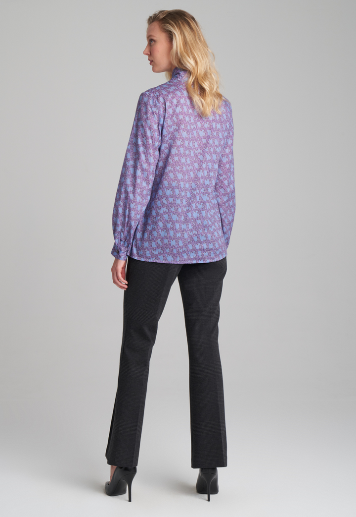 Woman wearing purple and blue bird printed cotton blouse and stretch knit plaid pants by Ala von Auersperg for fall 2022