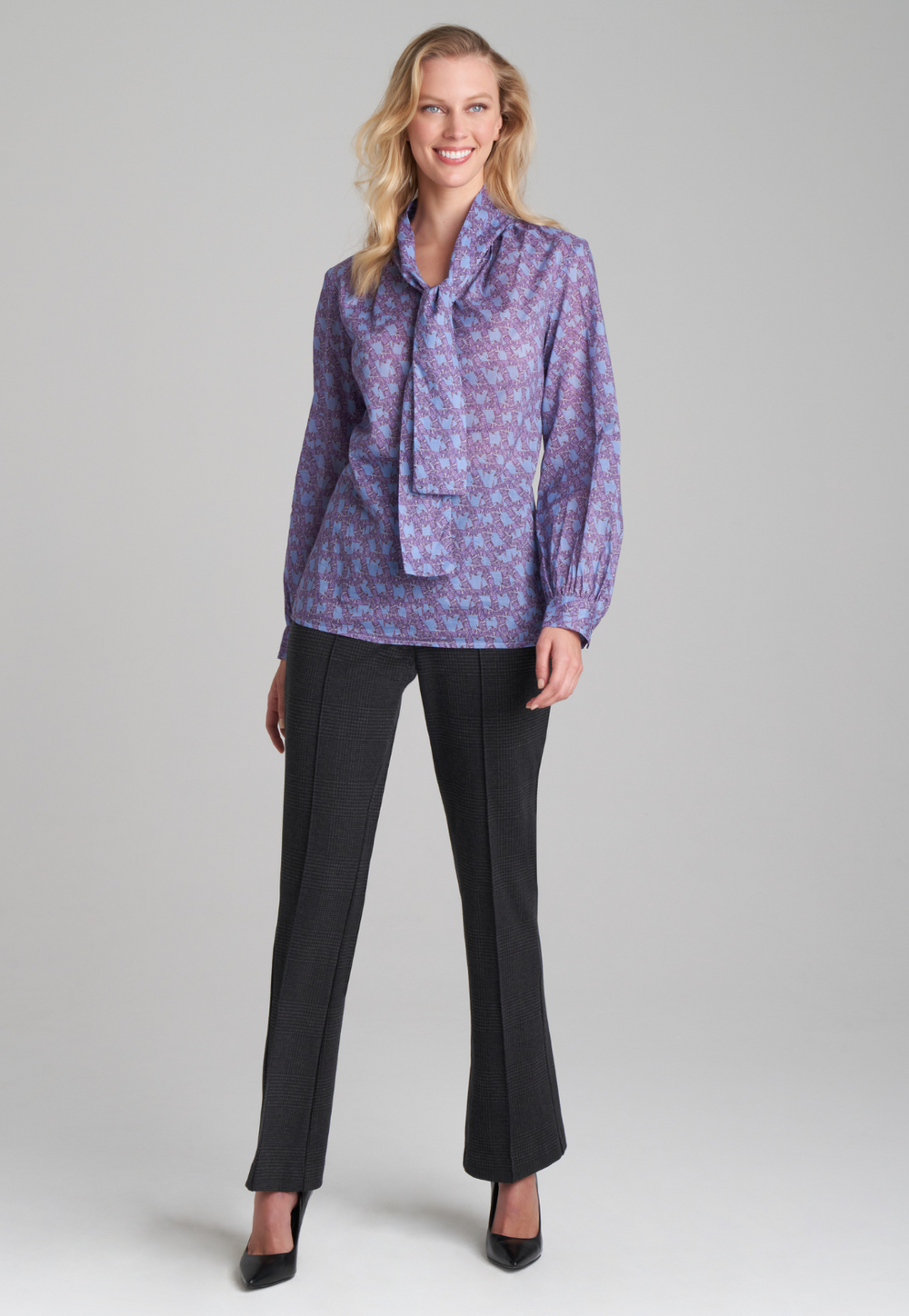 Woman wearing purple and blue bird printed cotton blouse and stretch knit plaid pants by Ala von Auersperg for fall 2022