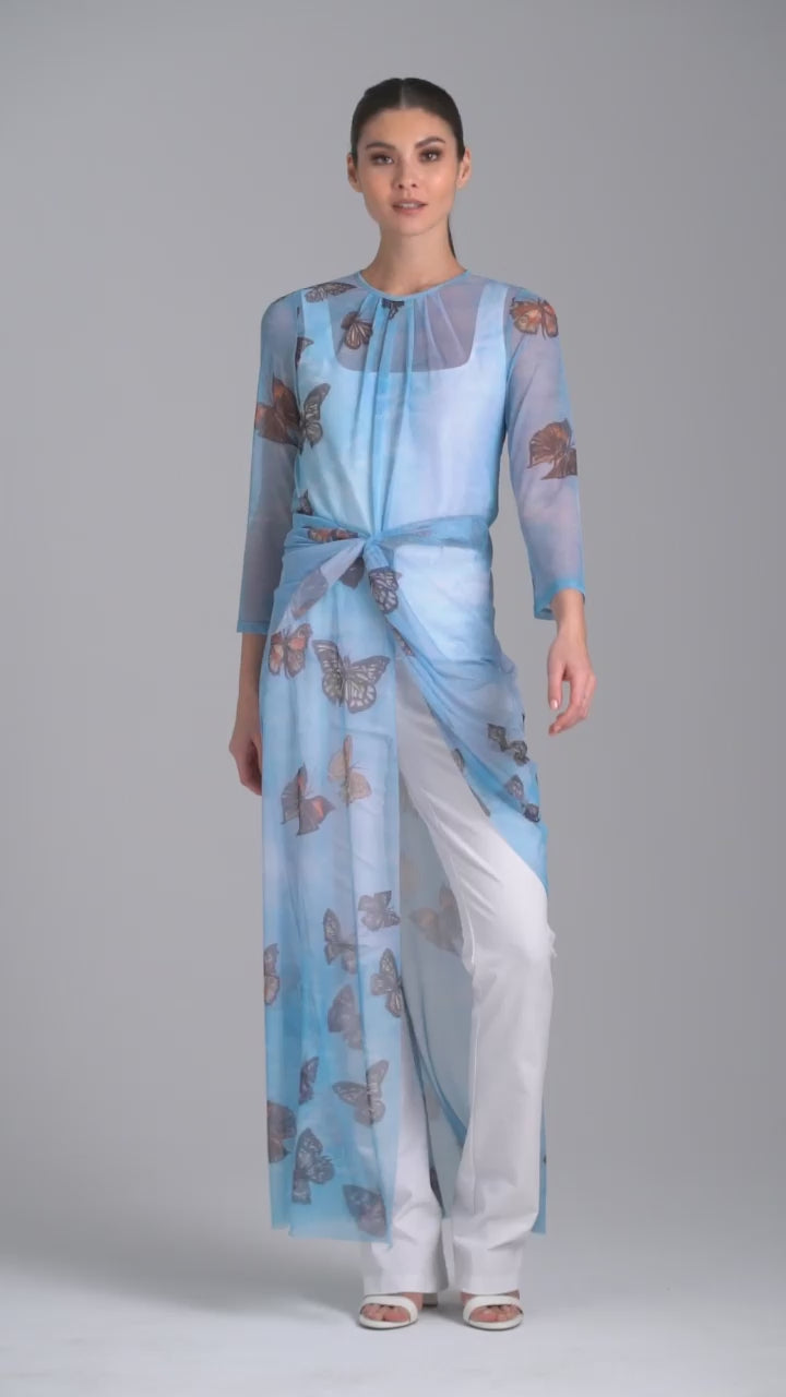 Woman wearing mesh blue butterfly printed asymmetrical topper over italian white stretch cotton tank top and pants by Ala von Auersperg for spring 2023