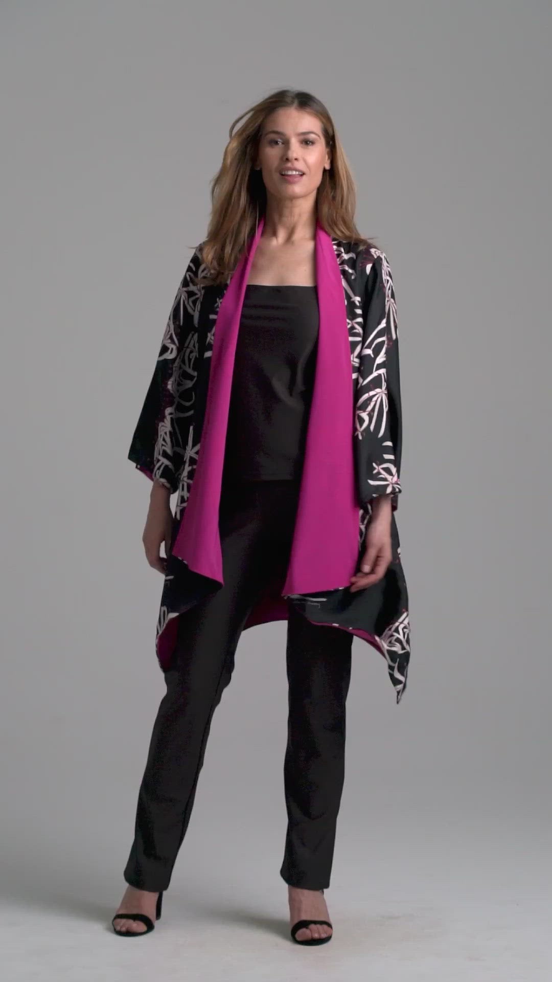 Woman wearing silk black spider lily printed reversible pink robe jacket over black stretch knit tank top and pant by Ala von Auersperg