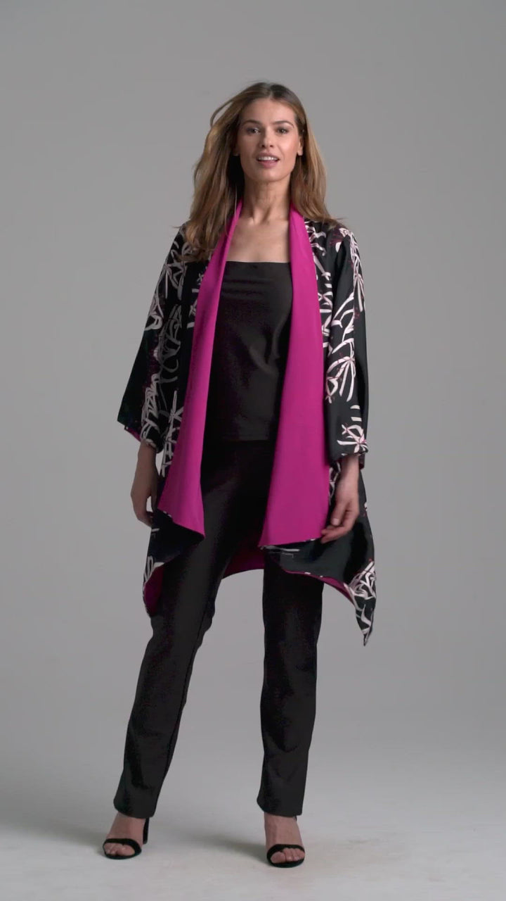 Woman wearing silk black spider lily printed reversible pink robe jacket over black stretch knit tank top and pant by Ala von Auersperg
