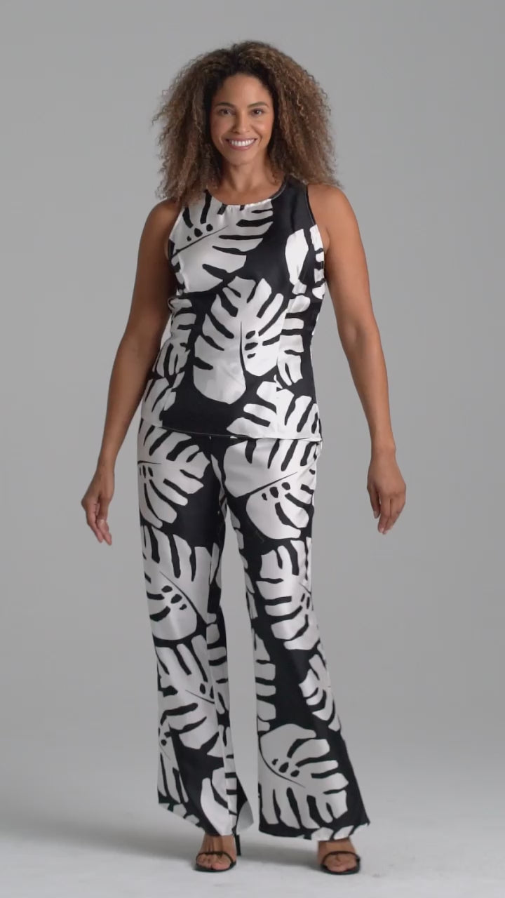 Woman wearing black and white palm leaf printed silk shell tank top and palm leaf black and white leaf printed silk wide leg pants by Ala von Auersperg for holiday 2022