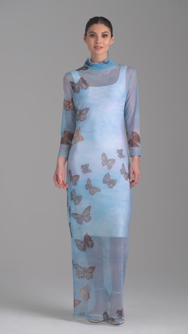 Woman wearing long mesh t shirt dress with turtleneck in blue butterfly printed over long stretch knit blue butterfly print dress by Ala von Auersperg for spring 2023