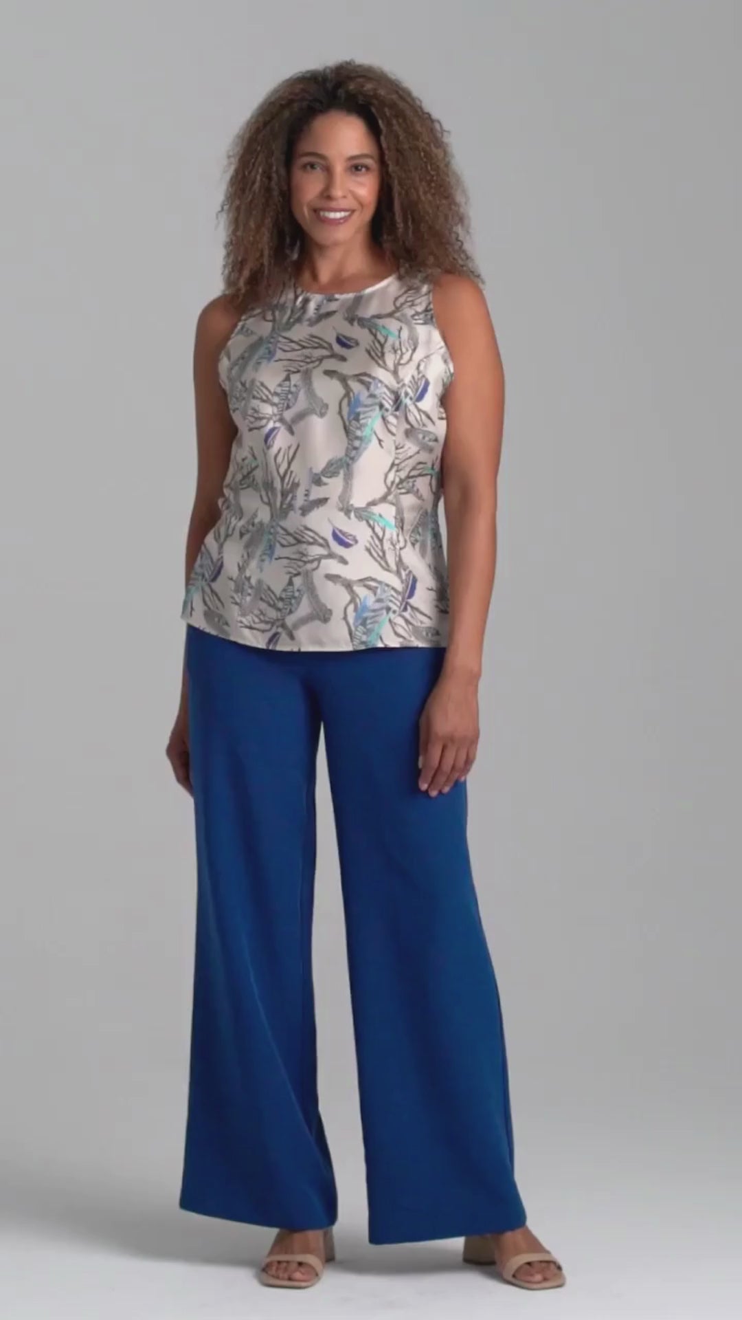 Woman wearing feather printed silk shell tank top and blue stretch knit pants by Ala von Auersperg for fall 2022